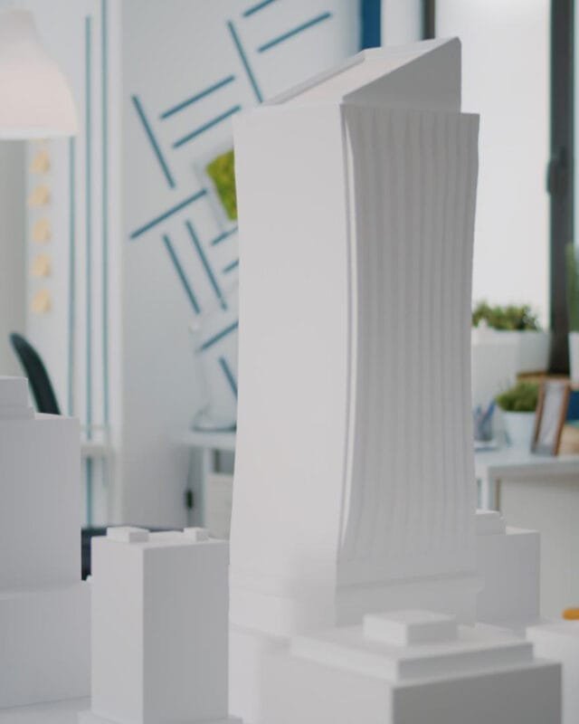 3D printed buildings Saudi Arabia: A model cityscape featuring a tall, modern building among smaller white structures, set in a stylish contemporary workspace.