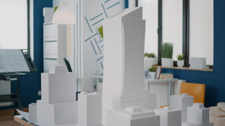3D printed buildings Saudi Arabia: A model cityscape featuring a tall, modern building among smaller white structures, set in a stylish contemporary workspace.